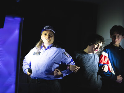 Eine Person in Polizeiuniform mit dem Logo "Genderpolizei" steht auf der Bühne und blickt dramatisch in die Ferne